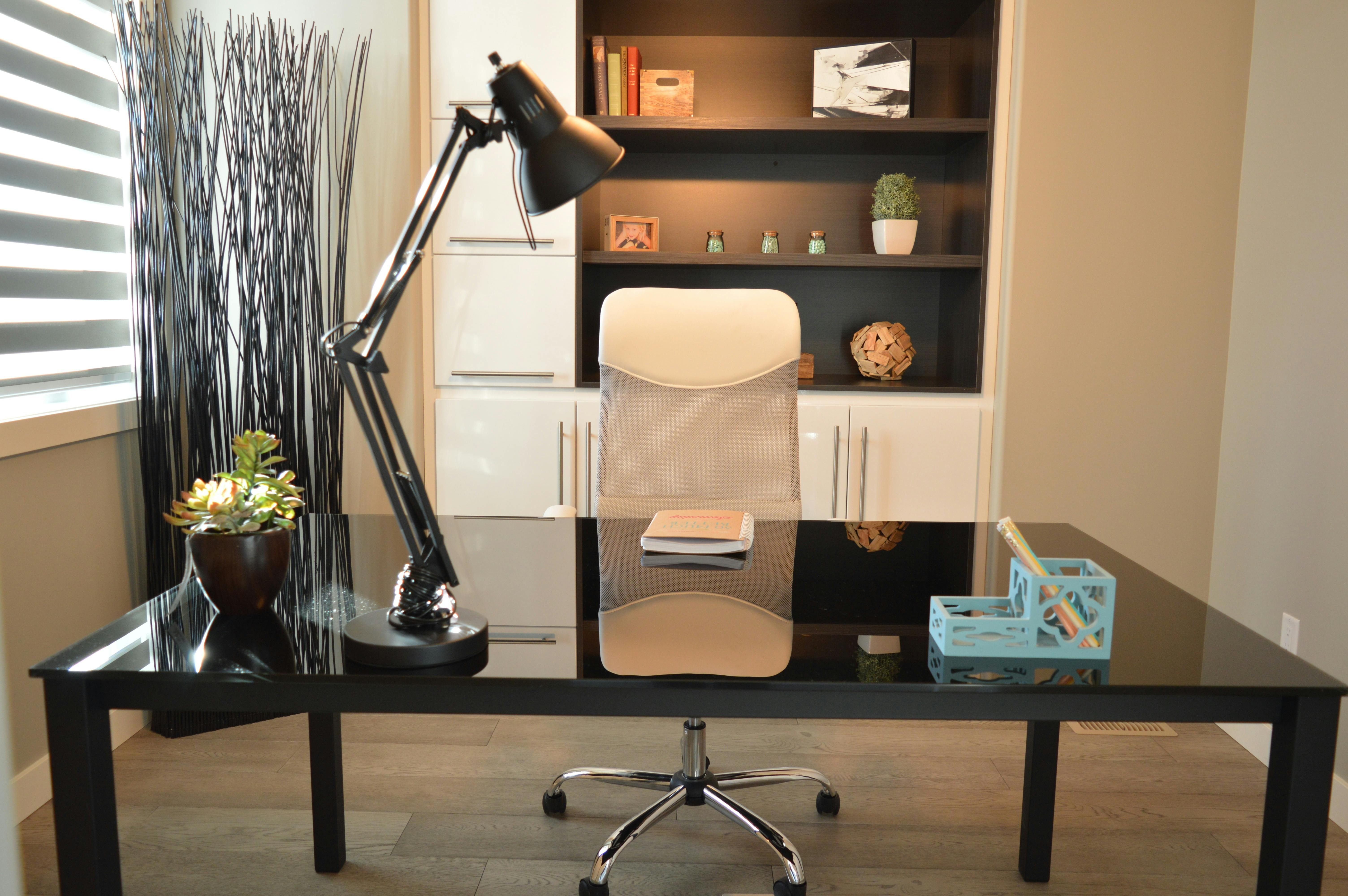 Home office with built-in white cabinetry, dark desk, and task lighting.