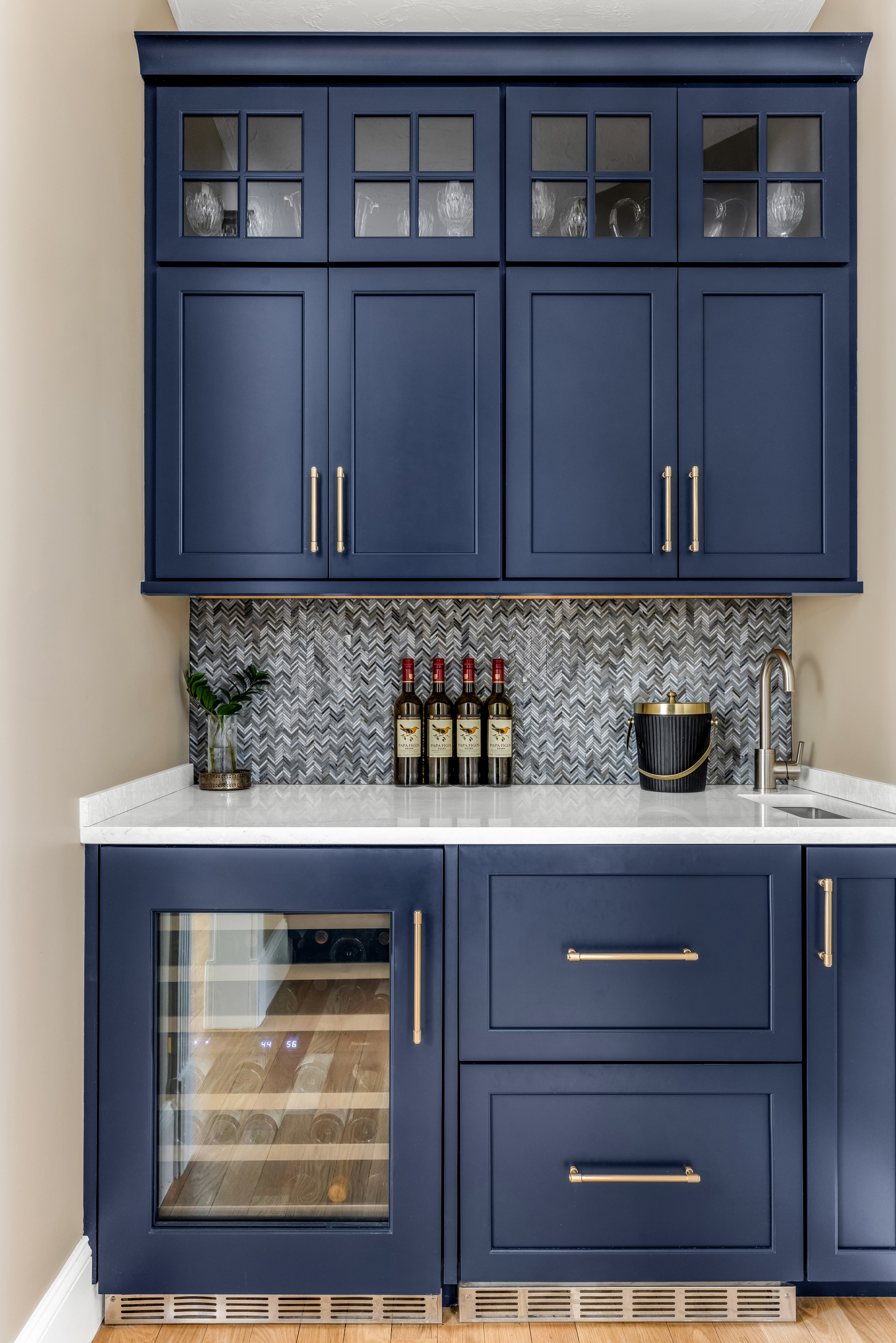 Butler's pantry with navy blue cabinetry, herringbone tile backsplash, and undermount sink.