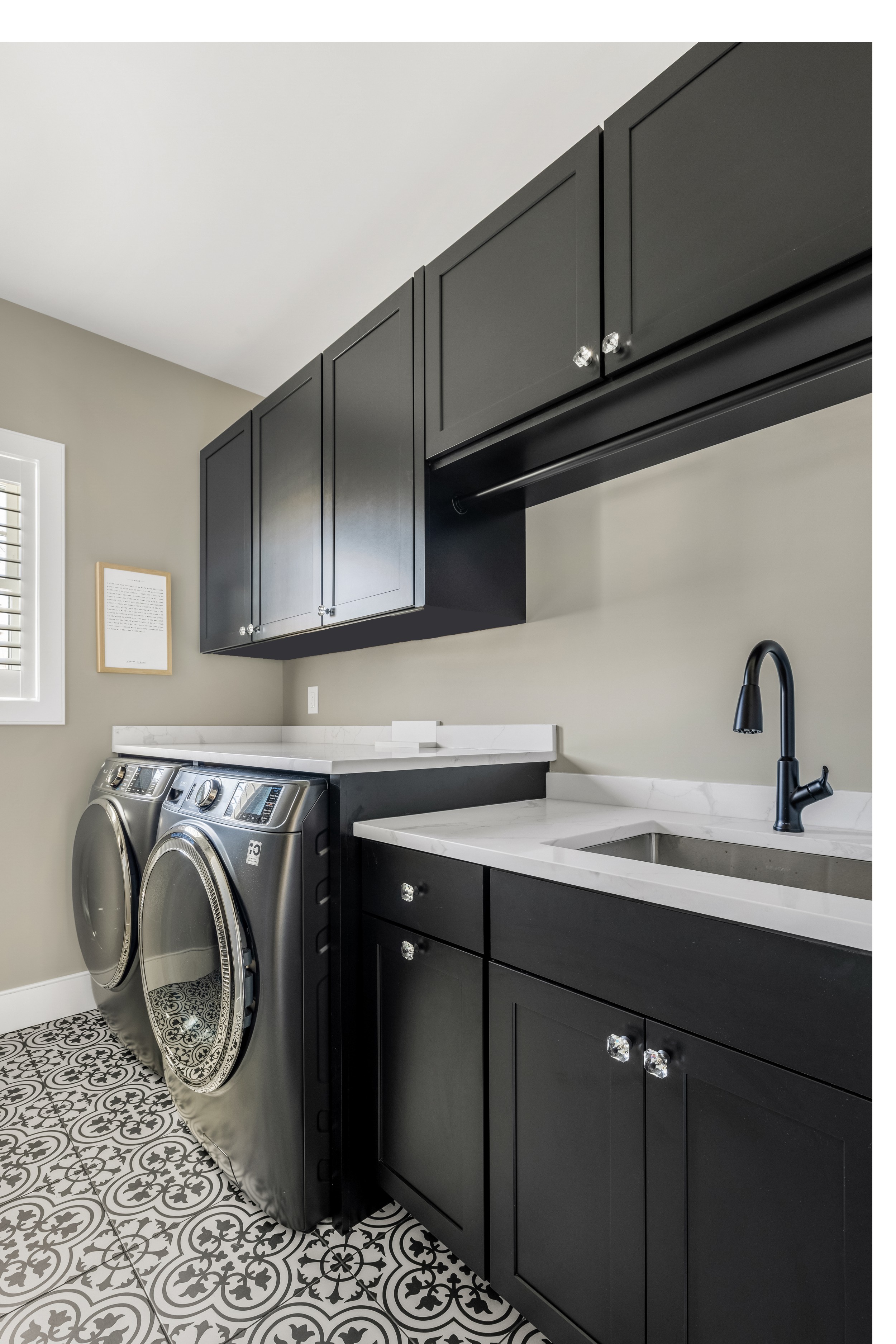 Laundry room with front-load washer and dryer, white countertop, and matte black faucet.