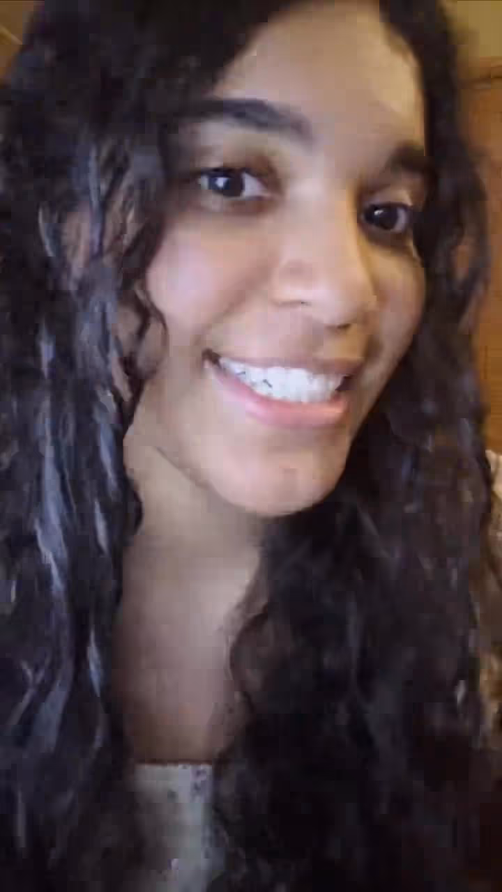 Woman with long dark hair smiling at church or hospital event with friendly expression naturally.