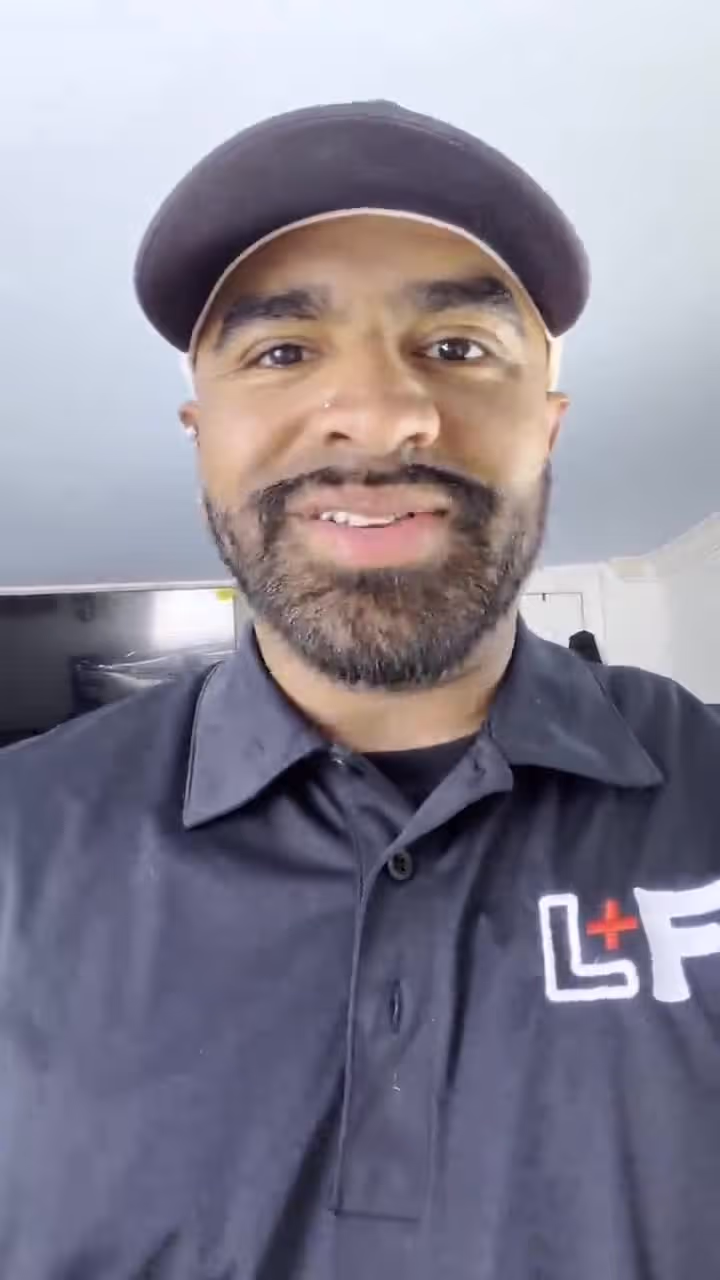 Man wearing dark shirt with medical logo, speaking at church or hospital event with friendly expression.