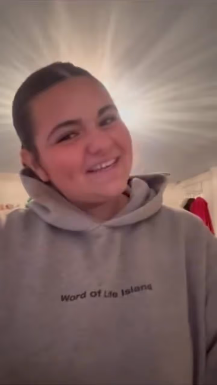 Woman wearing Word of Life Israel hoodie smiling at camera indoors at church or religious organization.