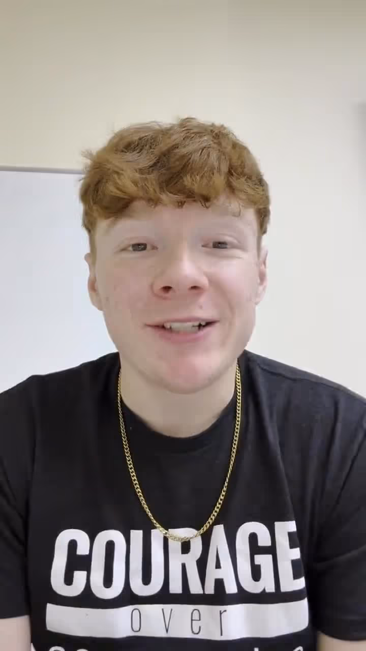 Young man with red hair wearing a courage over fear t-shirt and gold chain necklace.