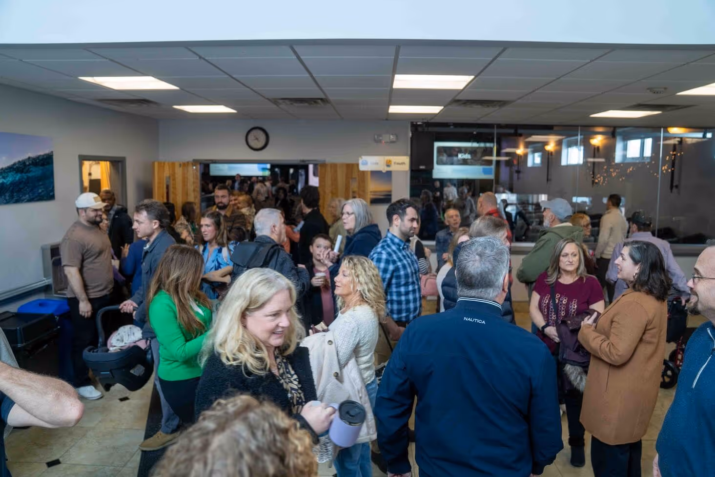 Crowd of people gathered in a community room, possibly a church or hospital event space.