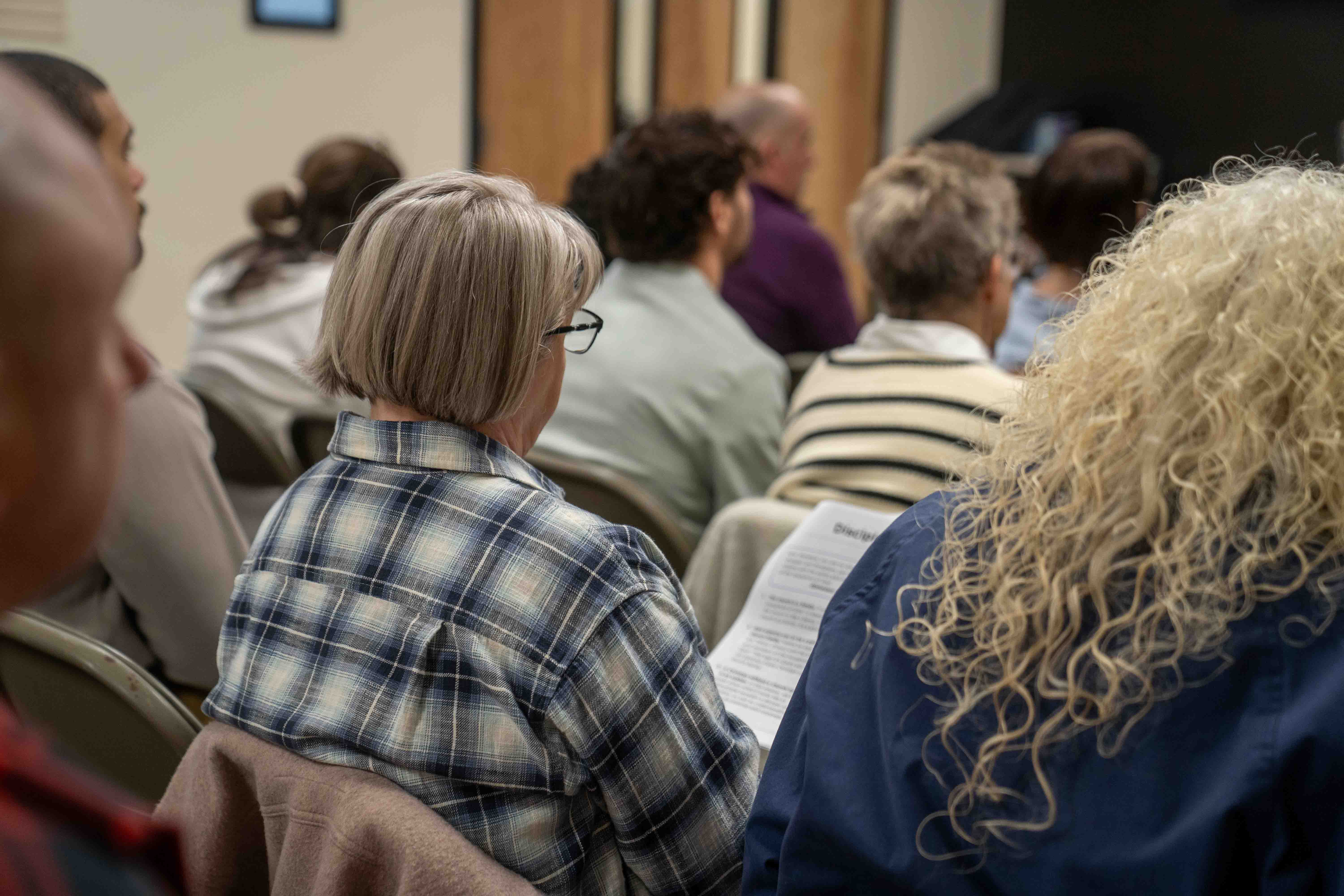 People sitting in chairs, attending church service or religious organization meeting or hospital support group.