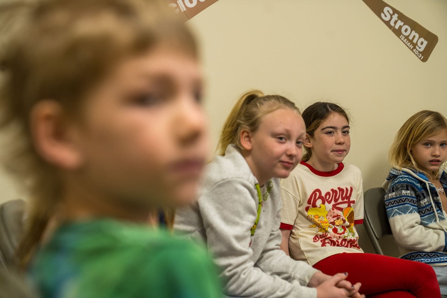 Young girls sitting together in a church or hospital setting, looking attentive and engaged.
