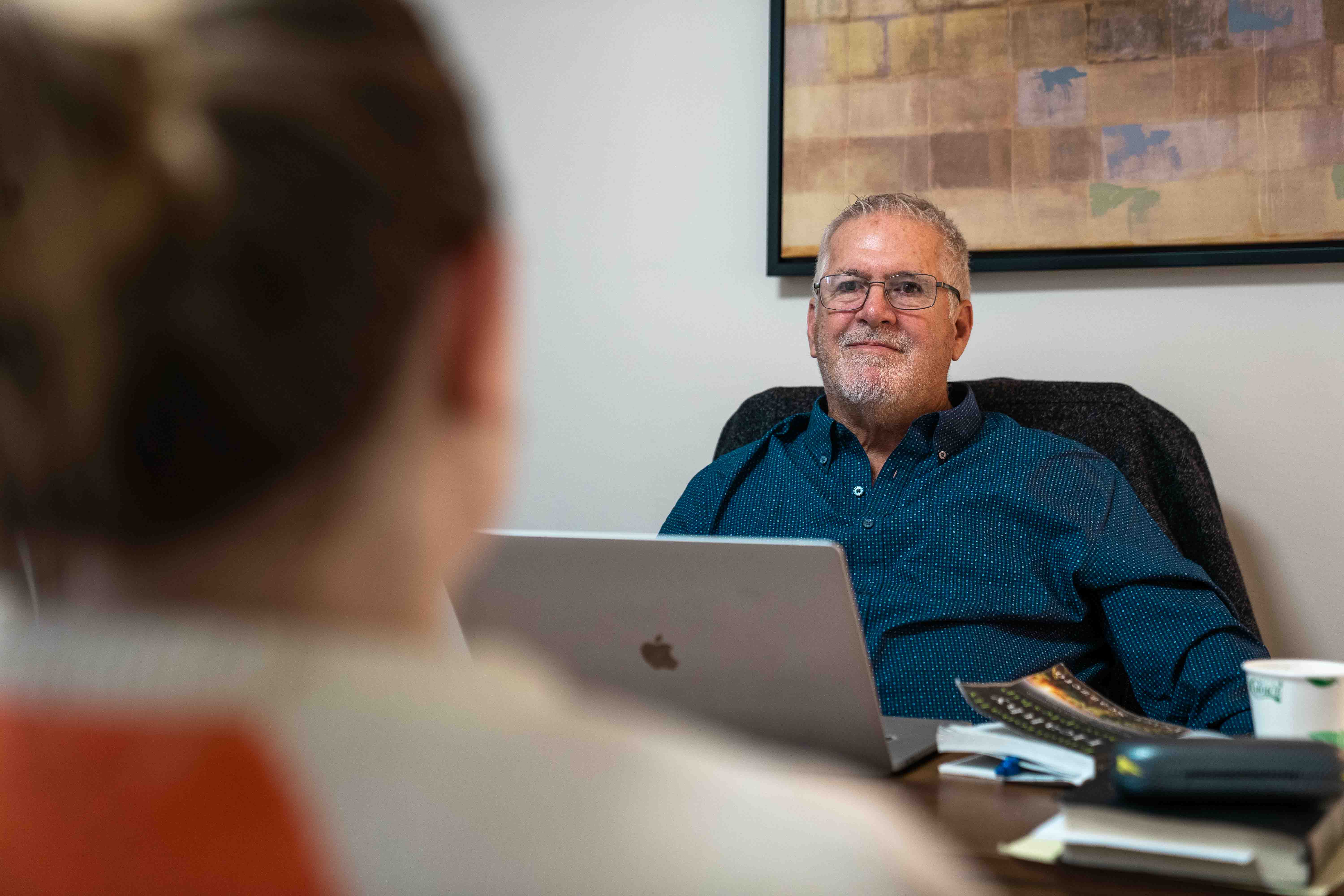 Man and woman in office setting with laptop and books, possibly hospital or church counseling.