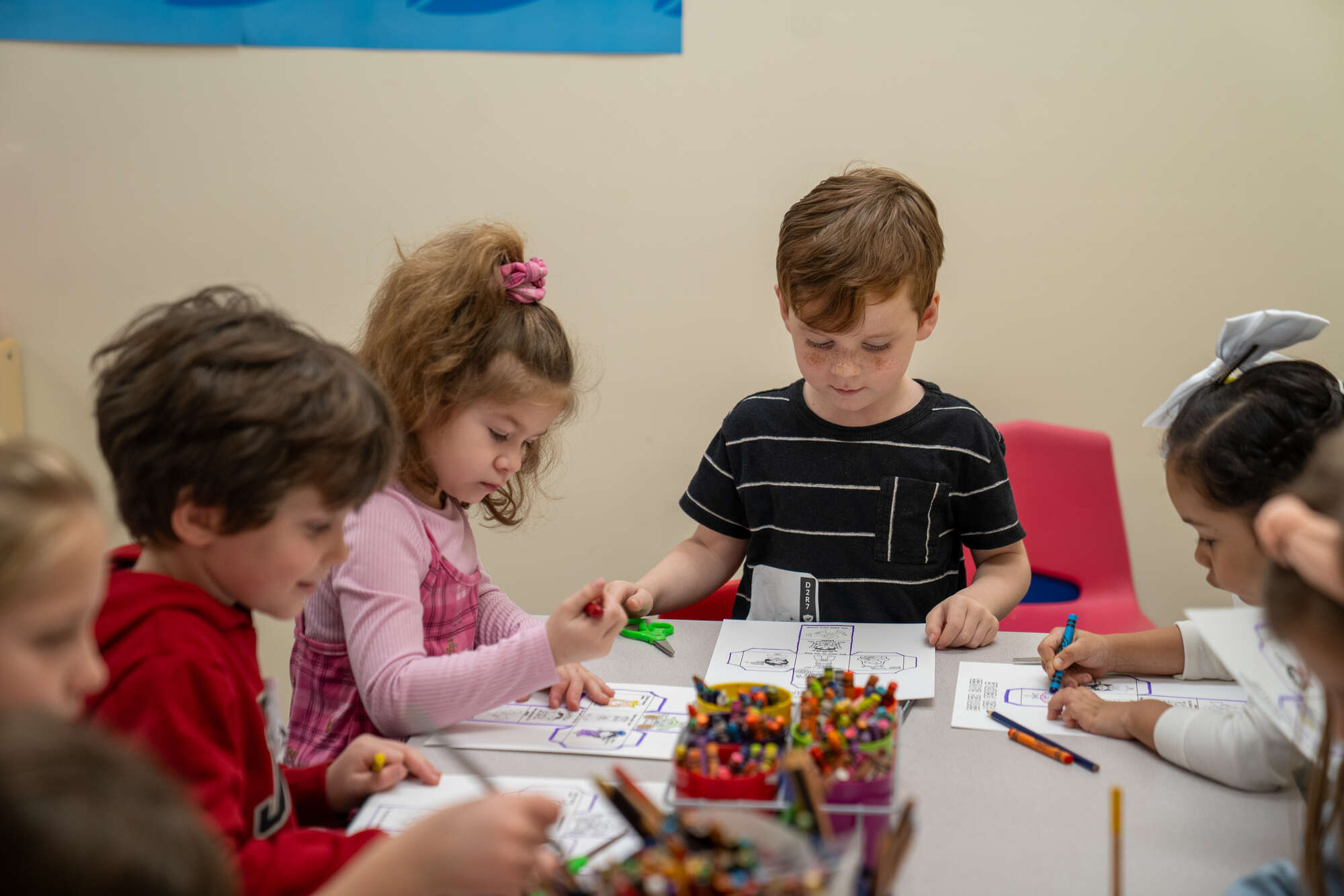 Children coloring at a table with crayons in a classroom or church activity setting together.