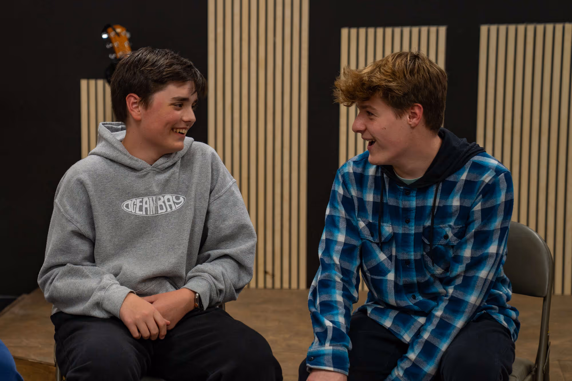 Teenagers sitting and smiling at each other in a church or hospital setting.