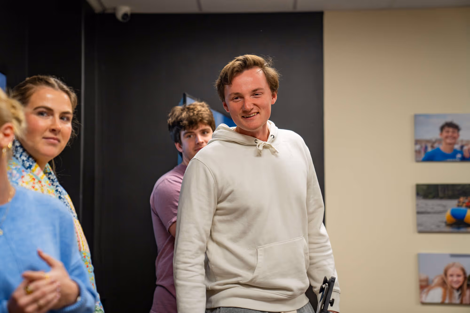 Young adults gathered in hospital or church community room smiling and socializing together informally.