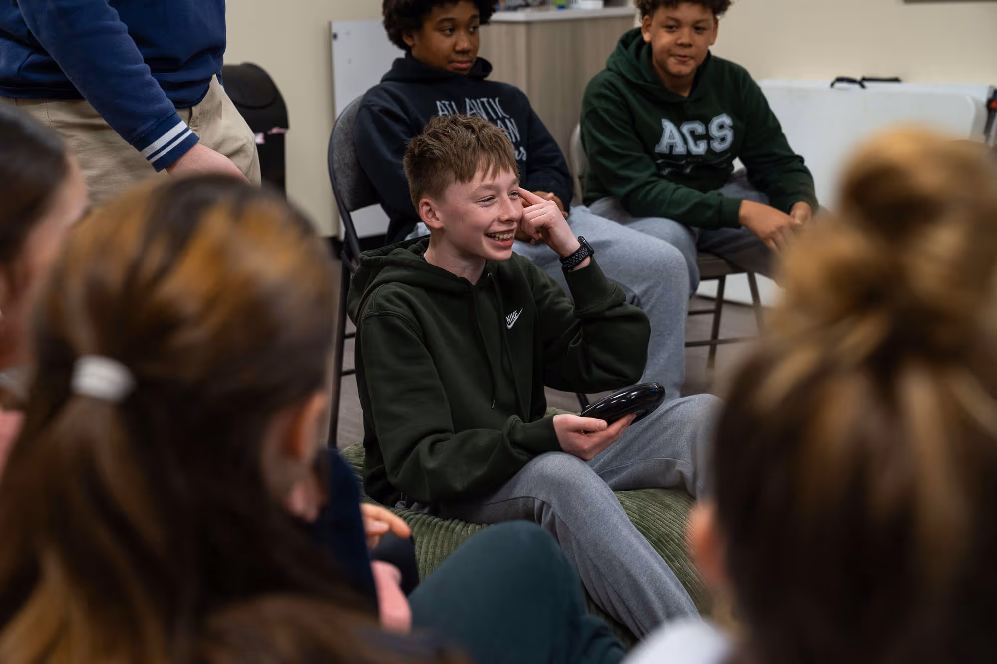 Teenagers sitting in a circle, engaged in a discussion or activity at a church or hospital.