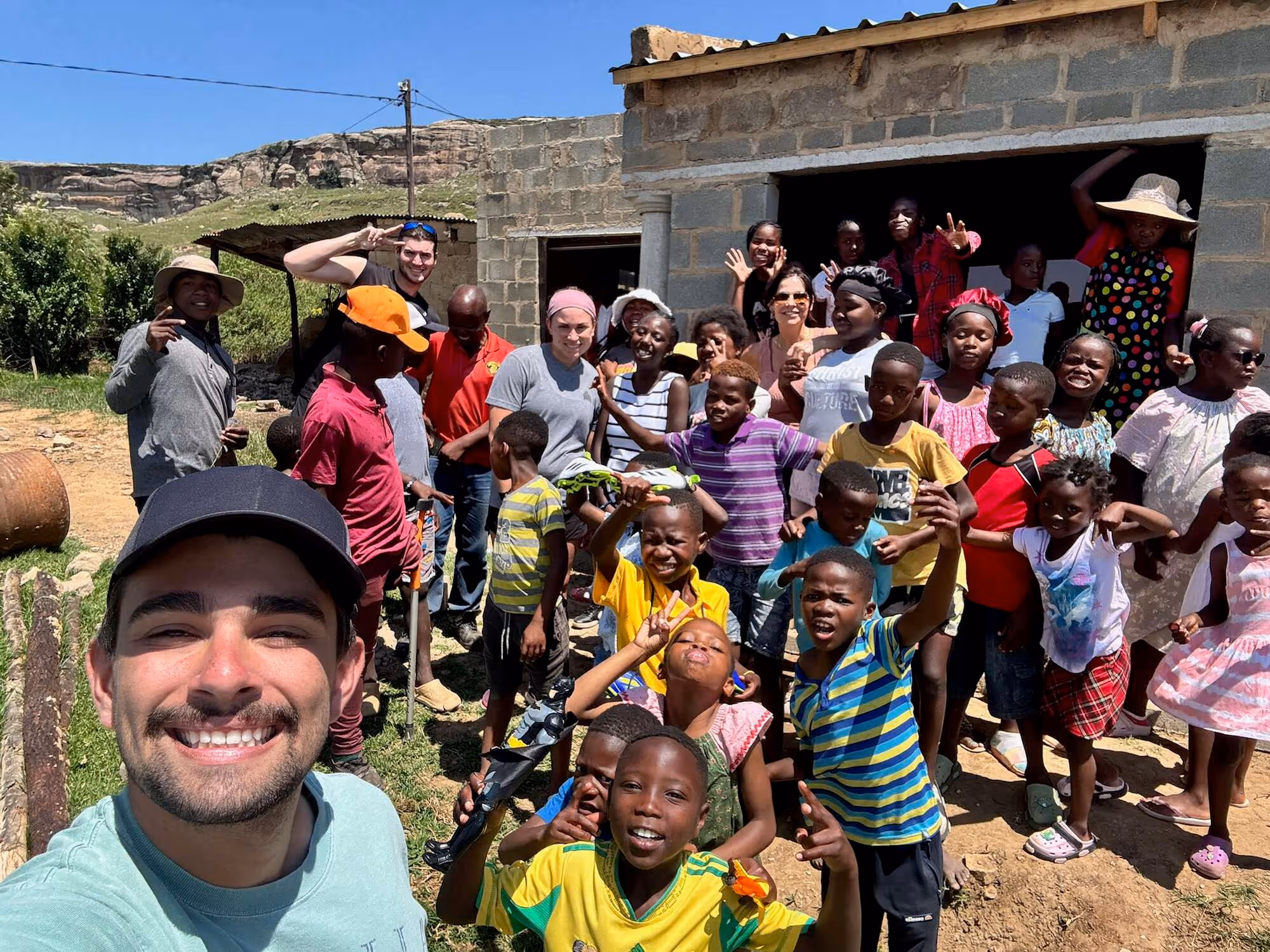 Church group and hospital volunteers with kids in a rural community smiling outdoors together happily.
