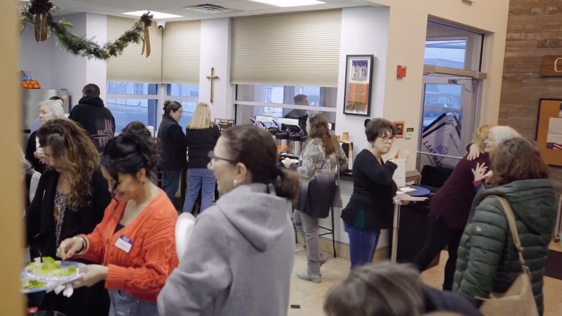 A group of people socialize and serve themselves food and drinks in a decorated indoor space.