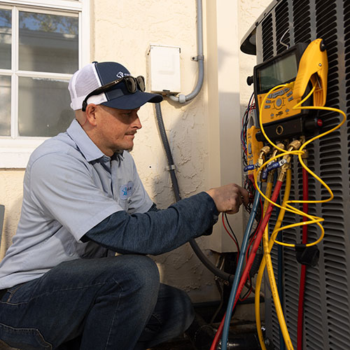 TrueBlue HVAC technician inspecting an air conditioning unit in Venice, Florida