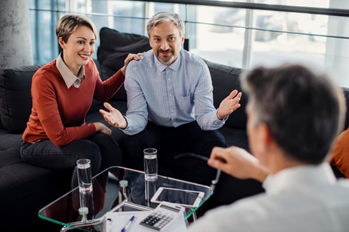Feliz pareja comunicándose con su agente de seguros en una reunión en la oficina.