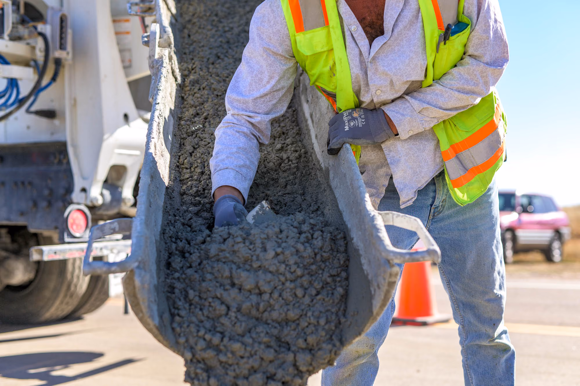 PMI Paving crew member guiding wet concrete out of a truck chute