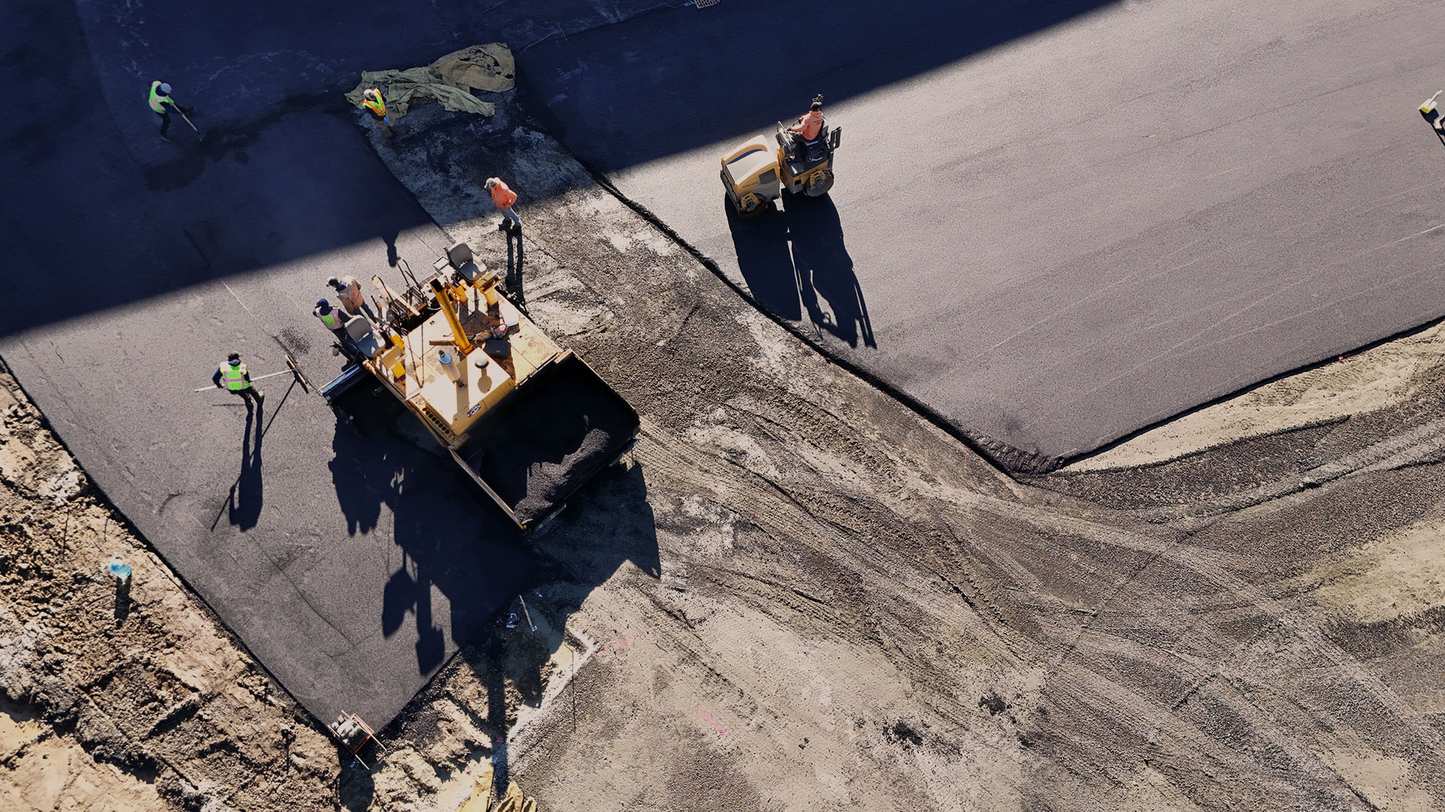 Wide aerial drone view of a full PMI Paving crew laying fresh asphalt