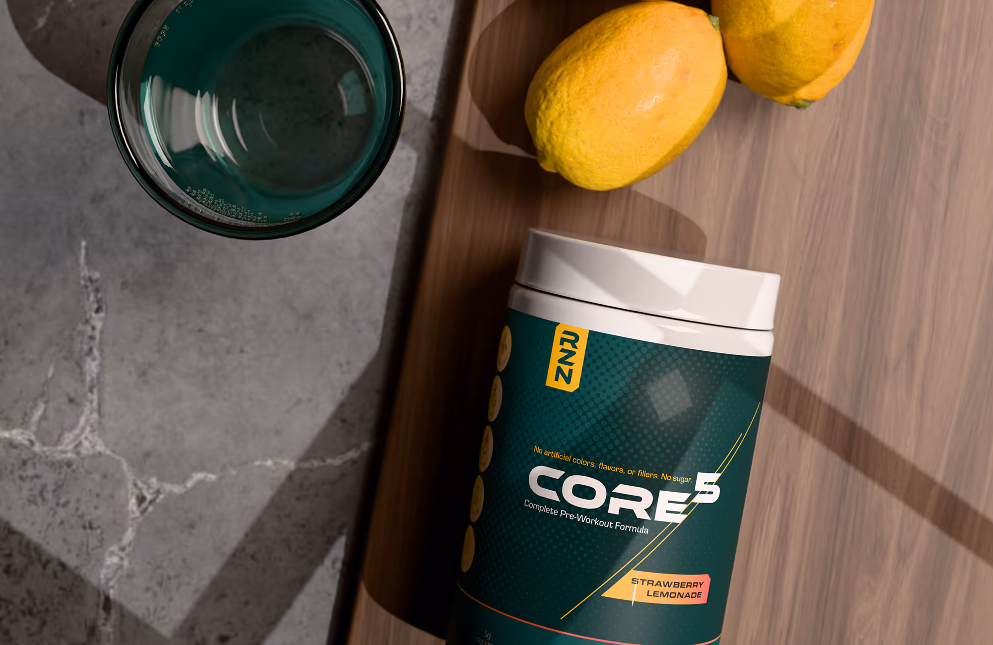 Container of CORE 5 pre-workout formula in strawberry lemonade flavor next to two lemons and a green glass on a wooden and stone surface.