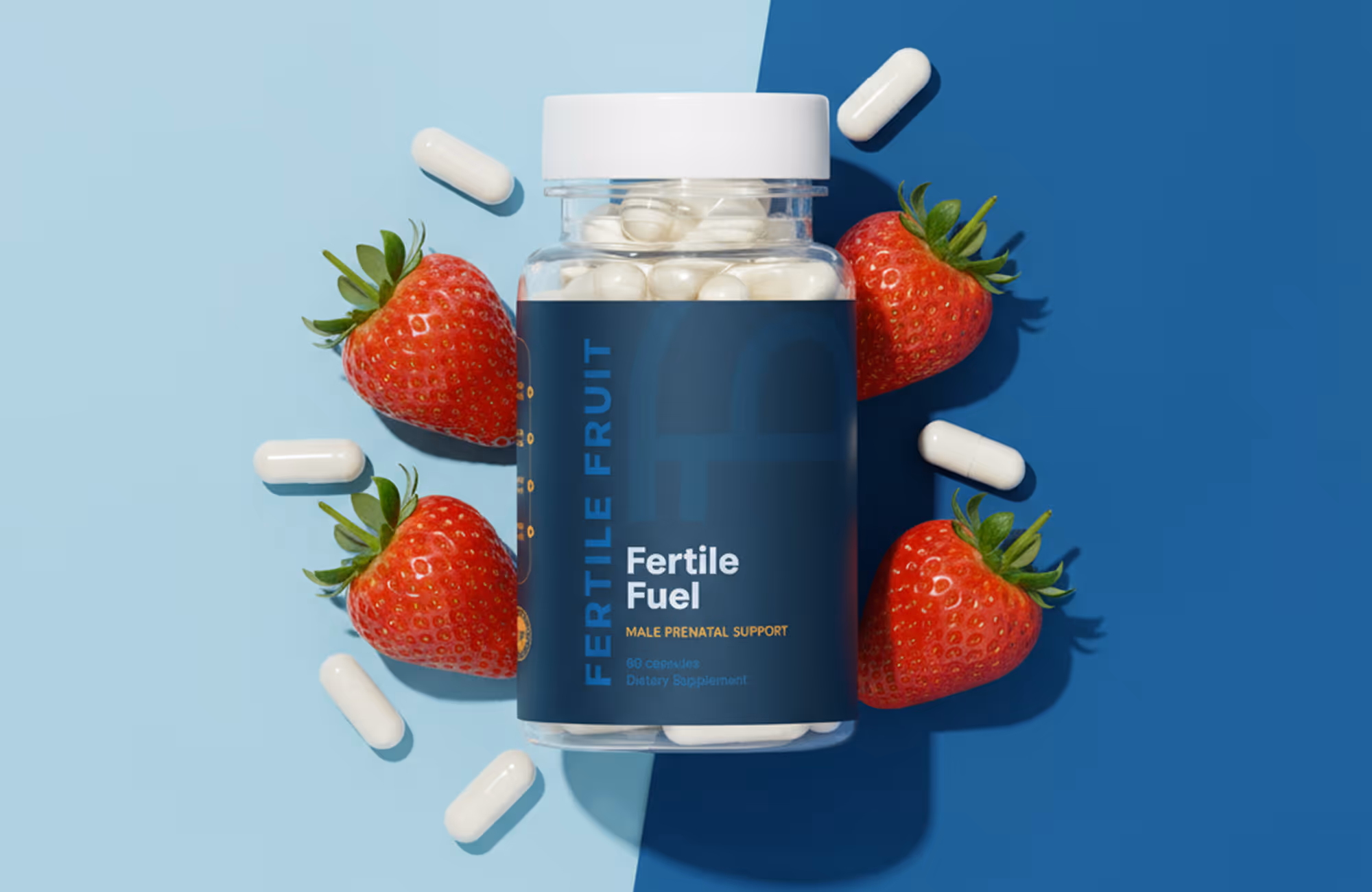 Bottle of Fertile Fruit Fertile Fuel male prenatal supplement capsules surrounded by fresh strawberries and white capsules on a two-tone blue background.