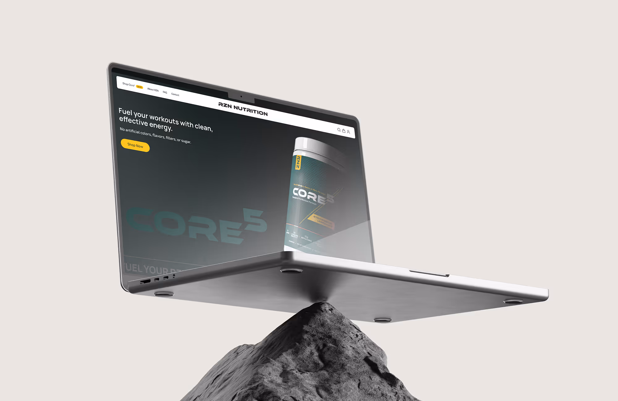 Laptop displaying RZN Nutrition website featuring CORE preworkout formula with a 'Shop Now' button, balanced on a rock.