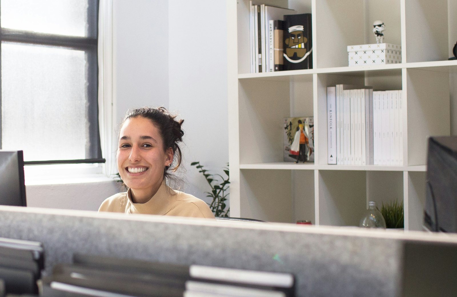 A smiling receptionist at a front desk in a bright studio
