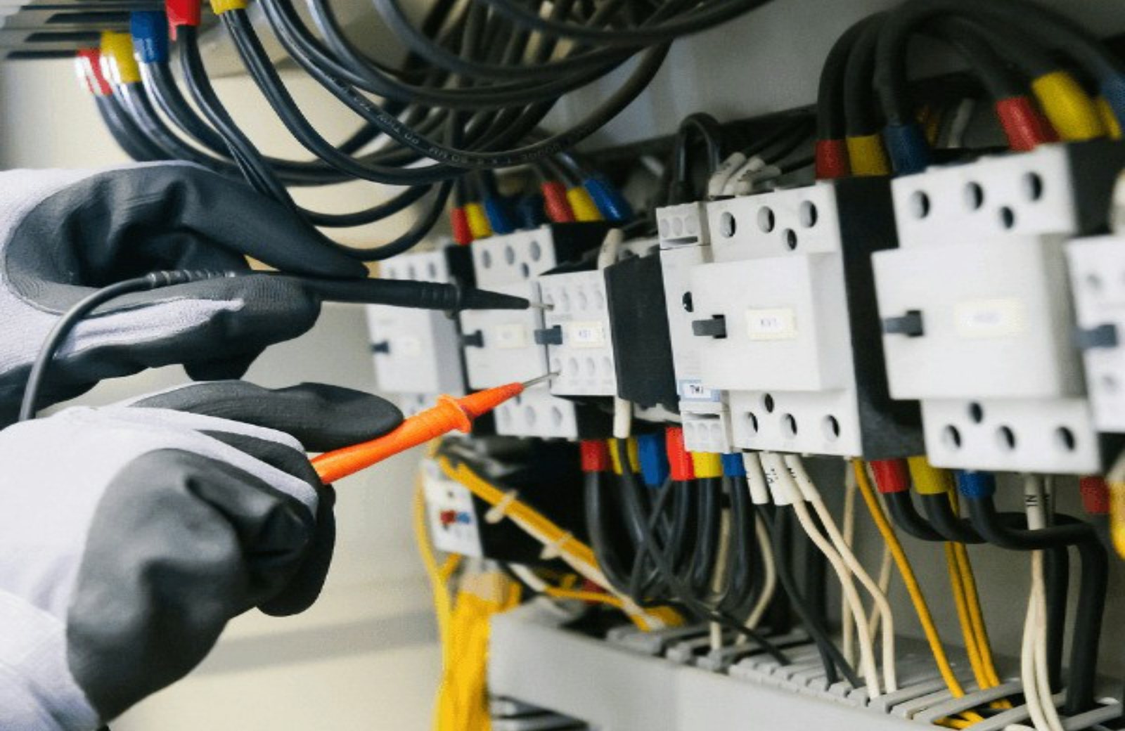 An electrician testing a control panel with a meter