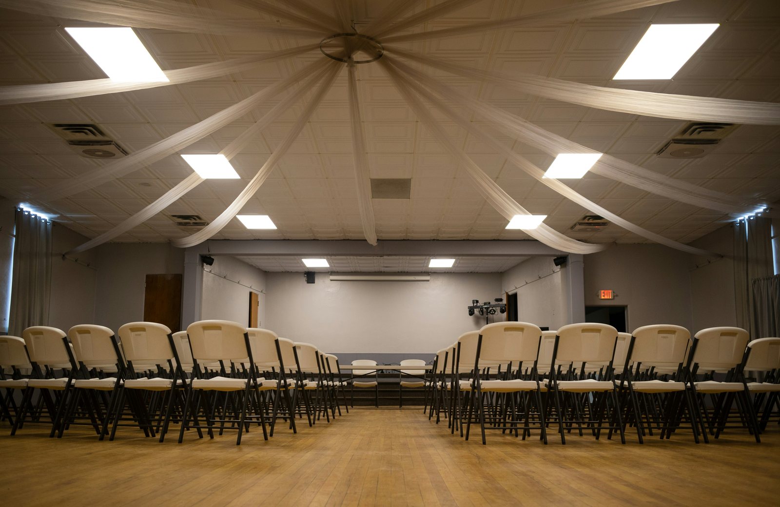 An empty event hall with rows of chairs facing a stage