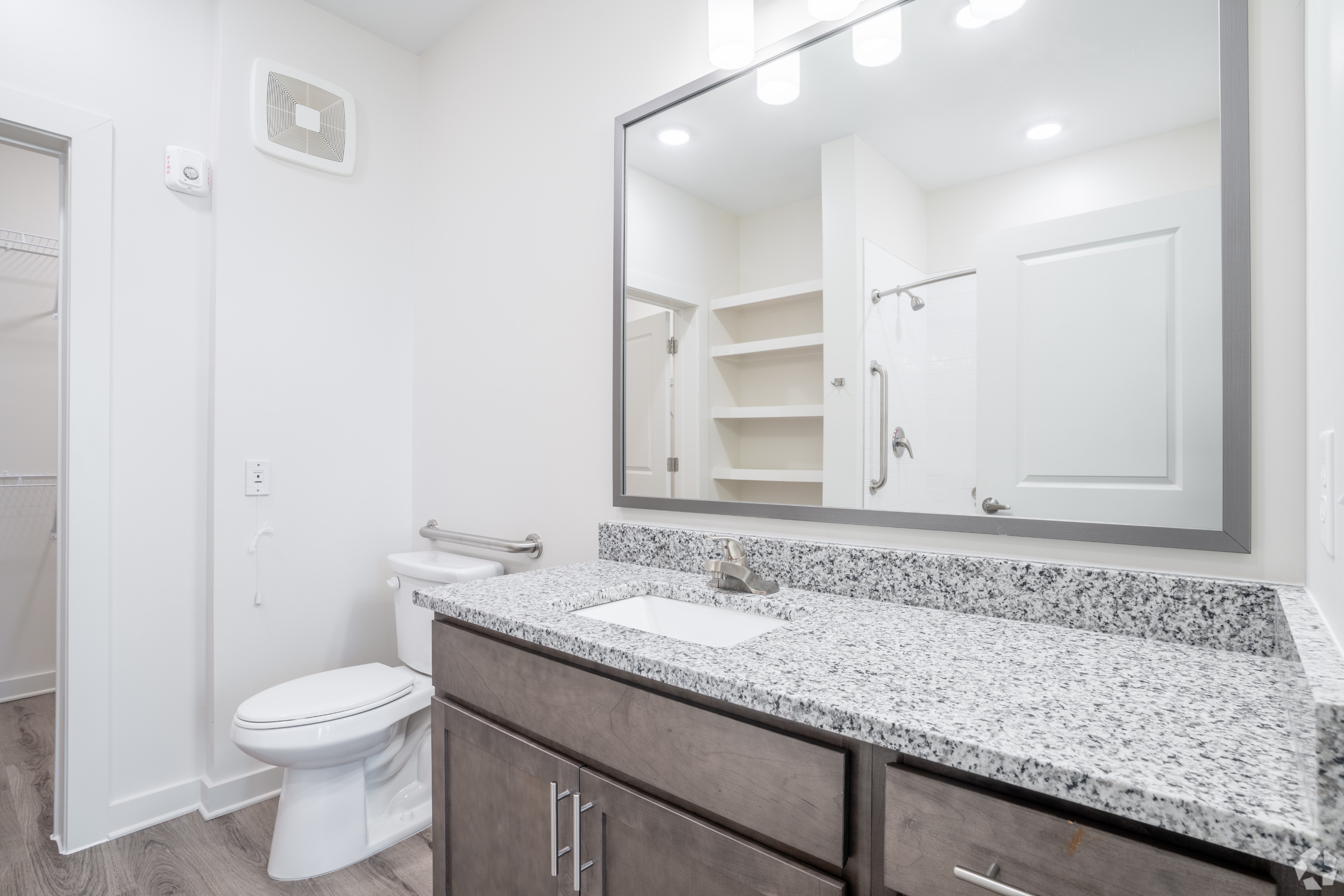 Bathroom with view of vanity, mirror, toilet and walk-in closet in the background