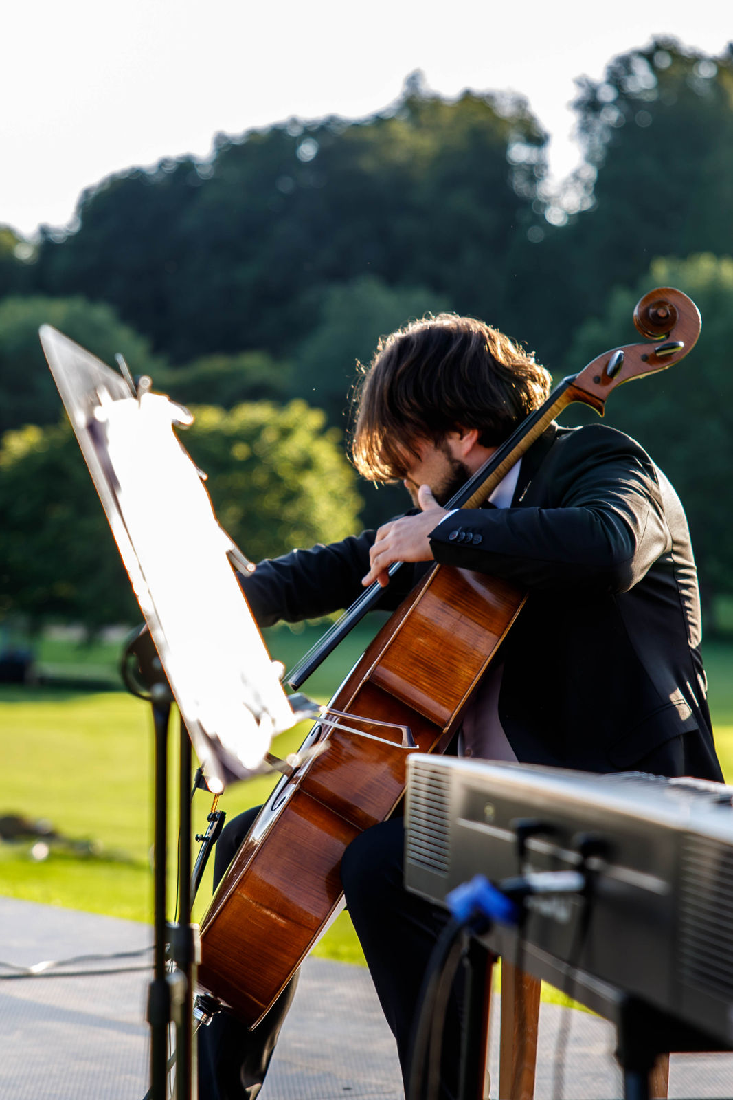 Person with short bob haircut wearing a white pleated-back shirt facing away against a dark background.