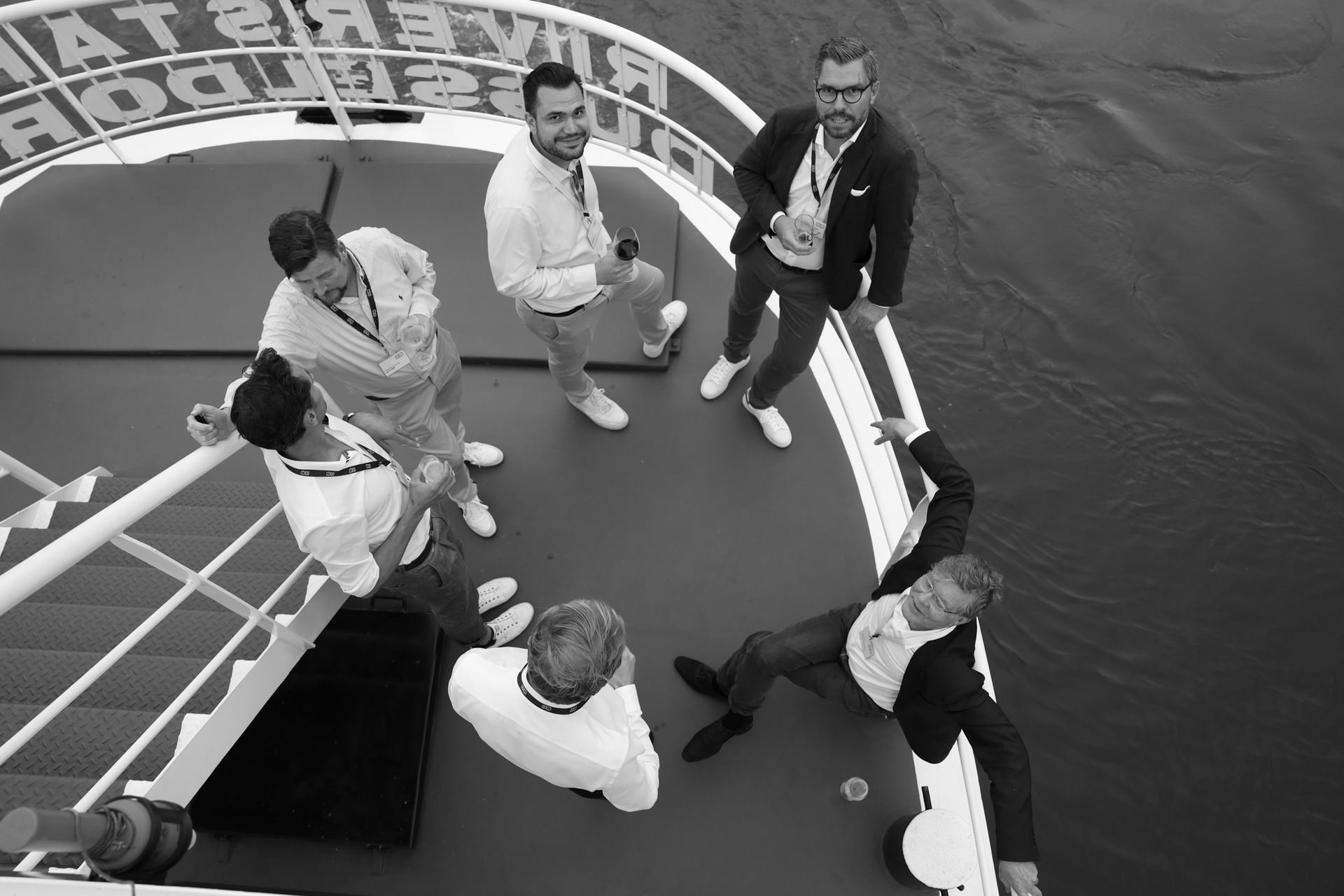 Person with short bob haircut wearing a white pleated-back shirt facing away against a dark background.