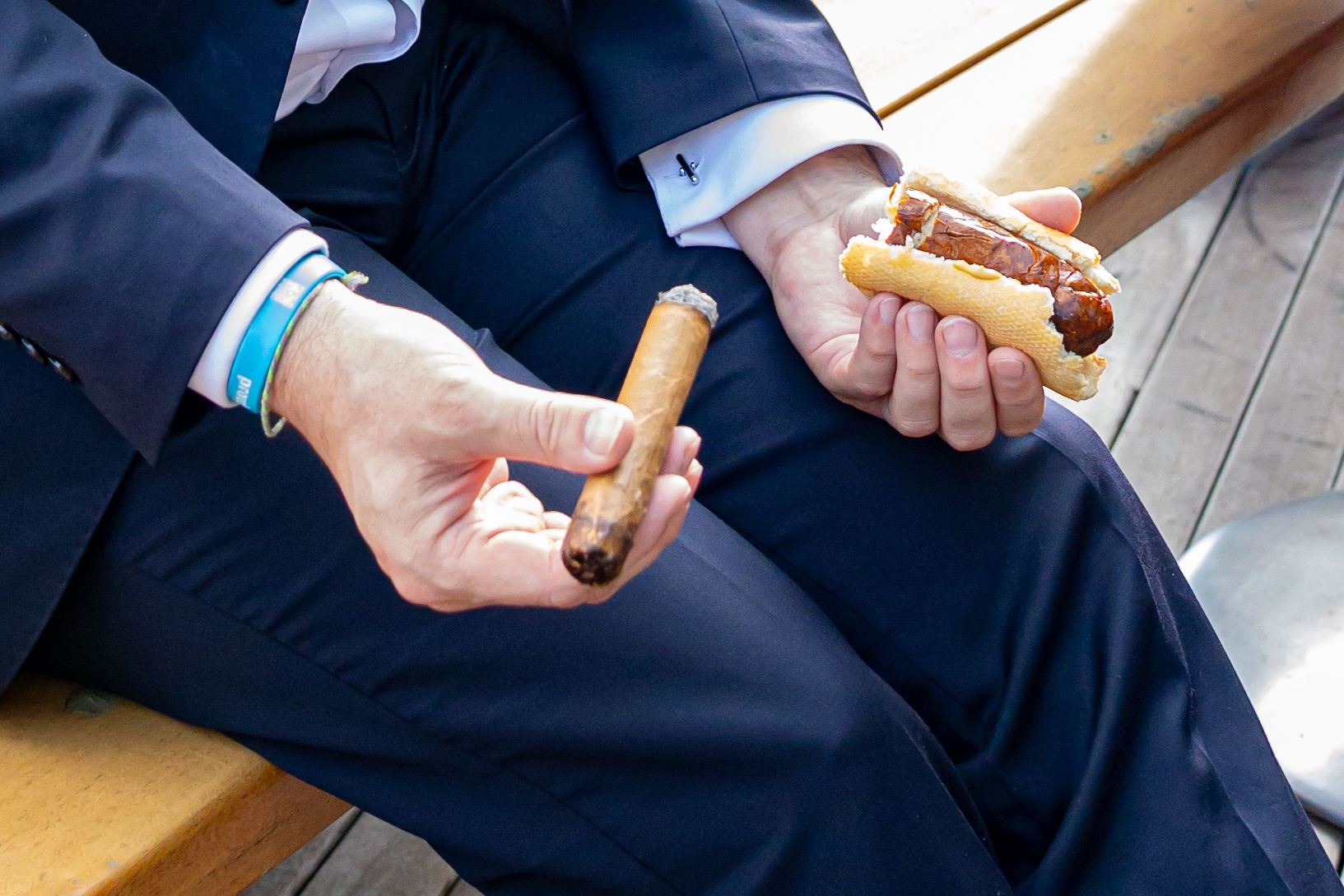 Person with short bob haircut wearing a white pleated-back shirt facing away against a dark background.