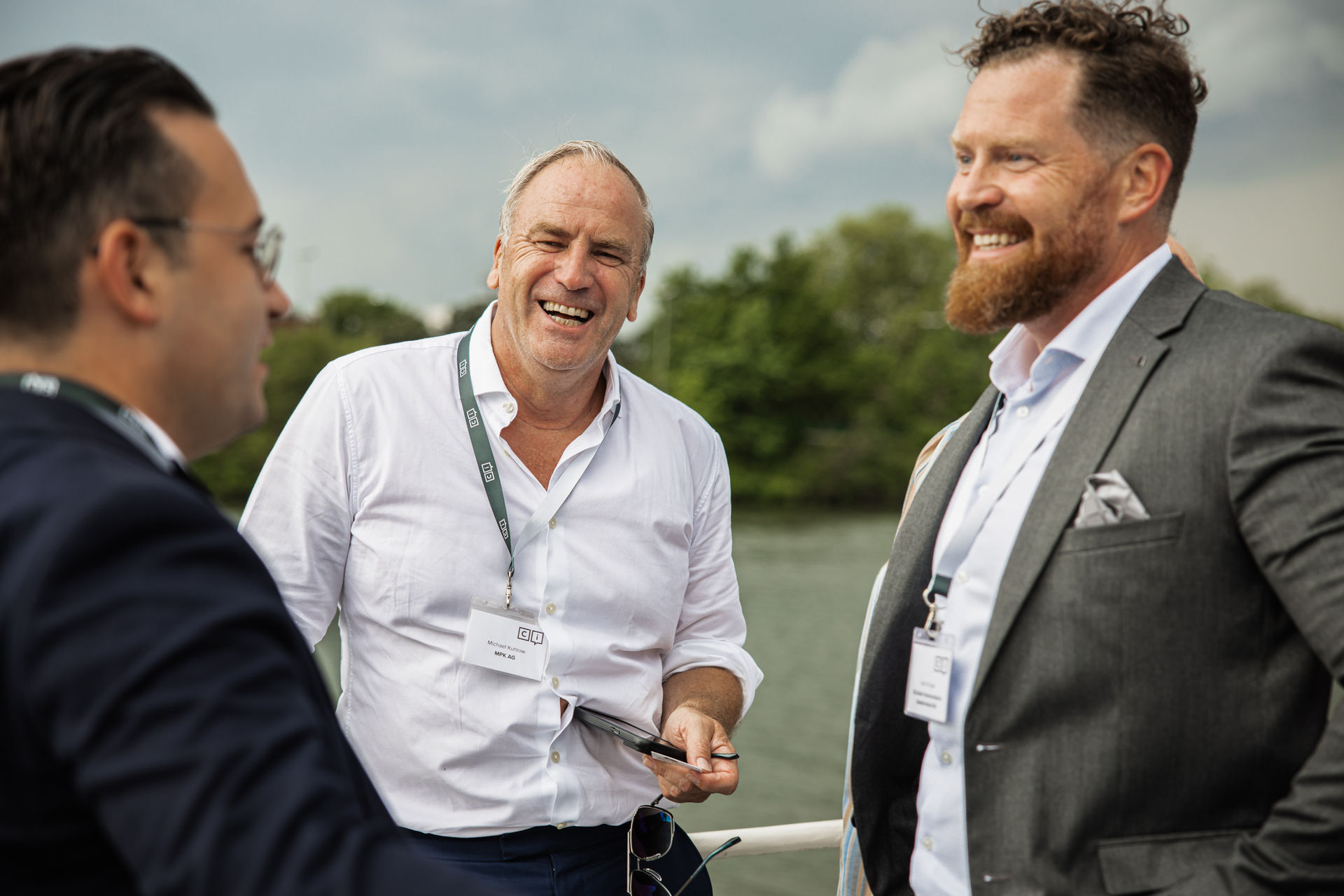 Person with short bob haircut wearing a white pleated-back shirt facing away against a dark background.