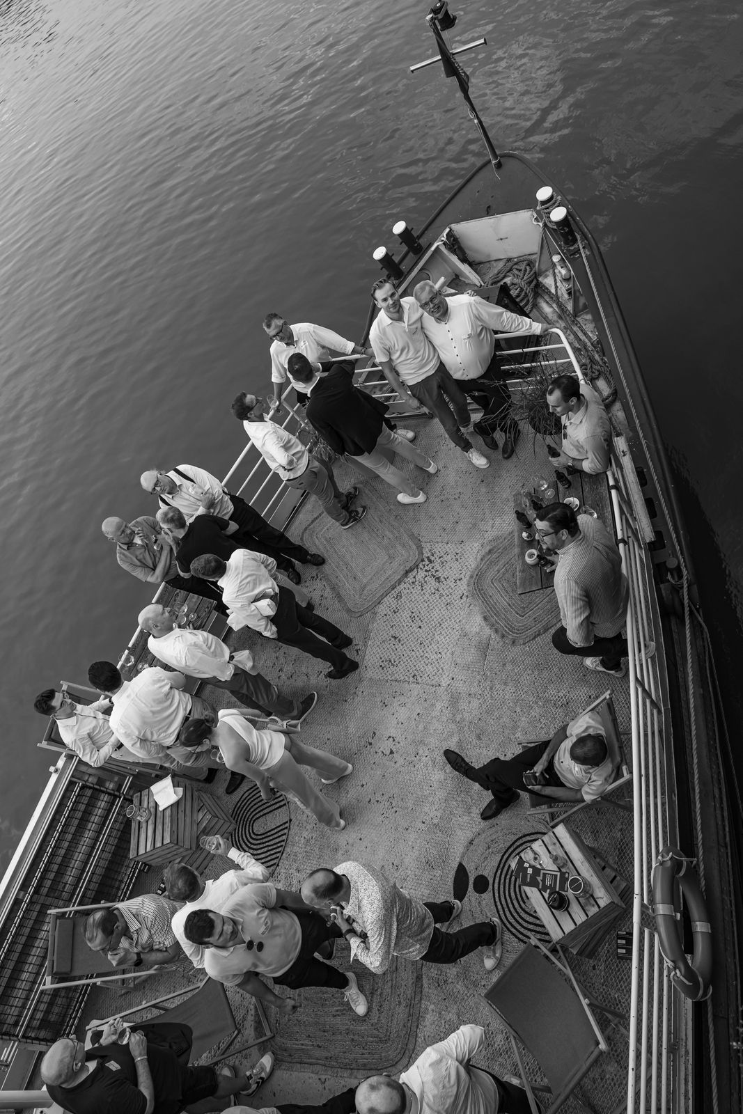 Person with short bob haircut wearing a white pleated-back shirt facing away against a dark background.