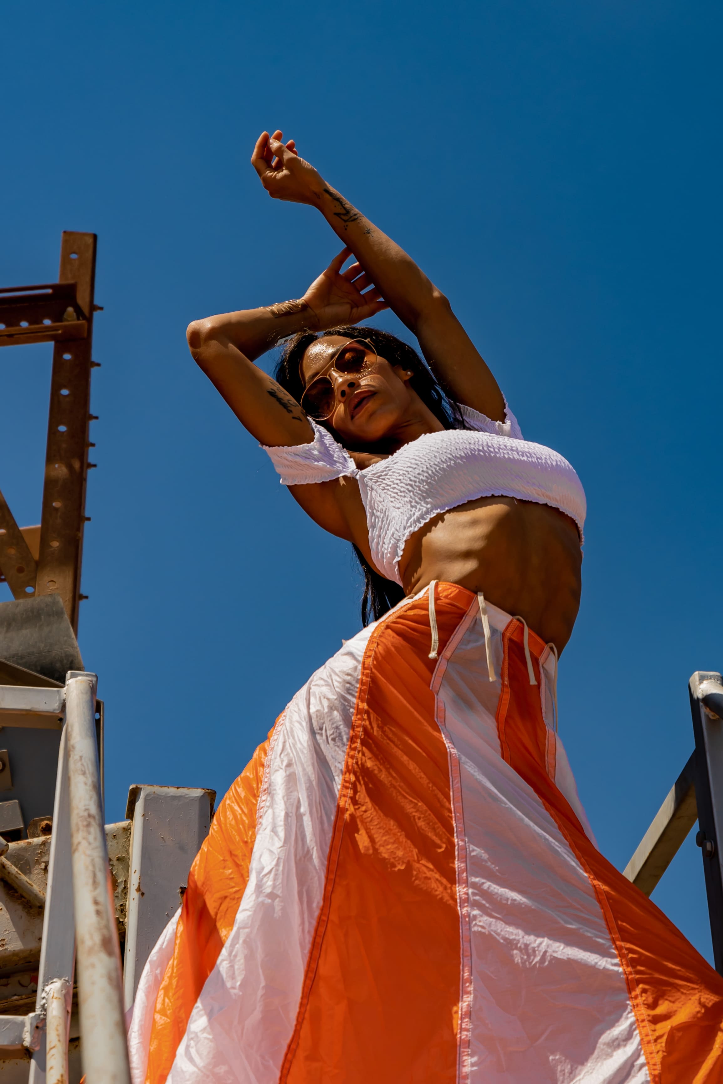 Person with short bob haircut wearing a white pleated-back shirt facing away against a dark background.