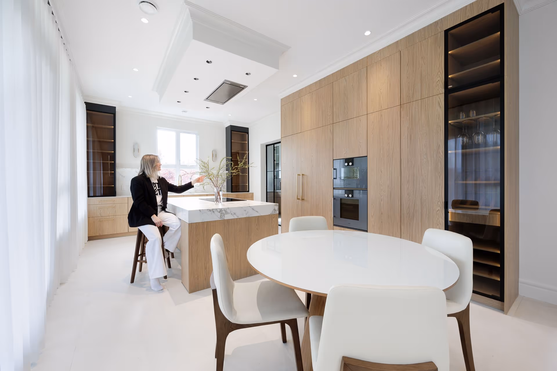 Modern minimalist kitchen interior with wood cabinetry, island seating and natural light