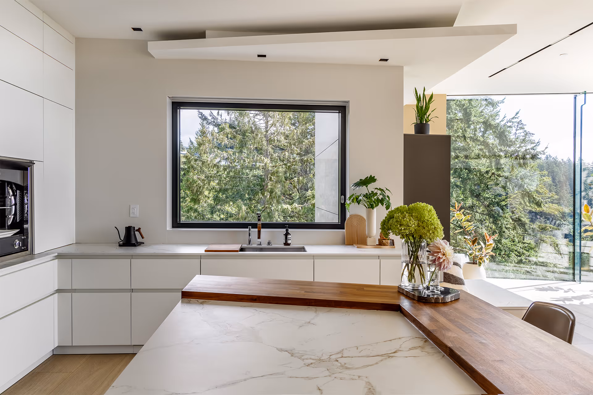 Modern minimalist kitchen interior with wood cabinetry, large windows and natural light