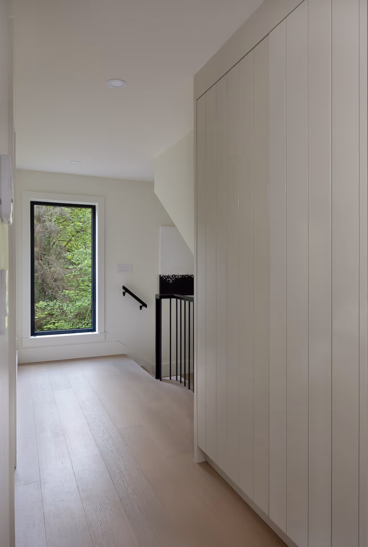 Minimalist hallway with built-in cabinetry and window view, natural light interior photography