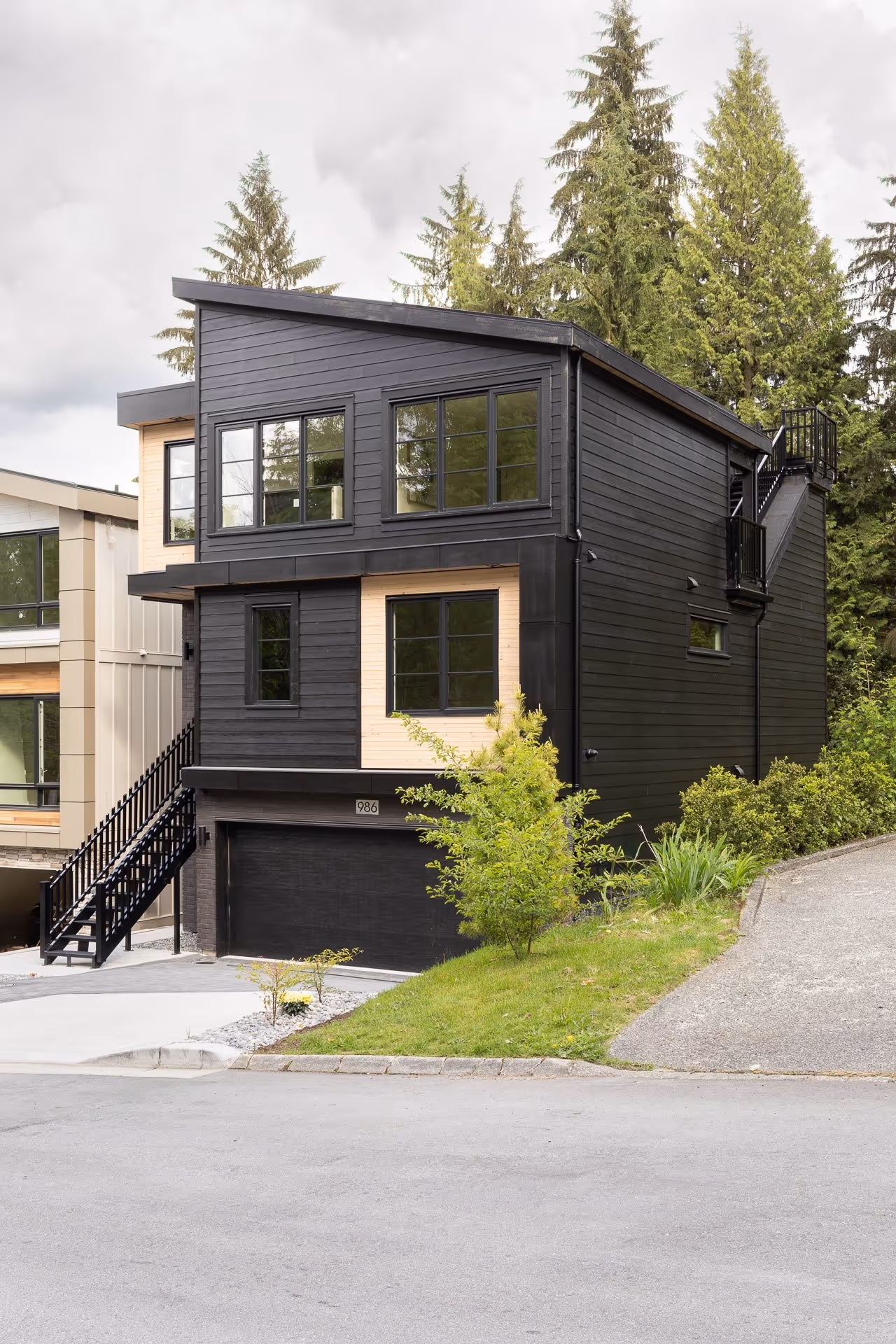 Modern black house exterior with wood accents and forest surroundings, residential architecture photography