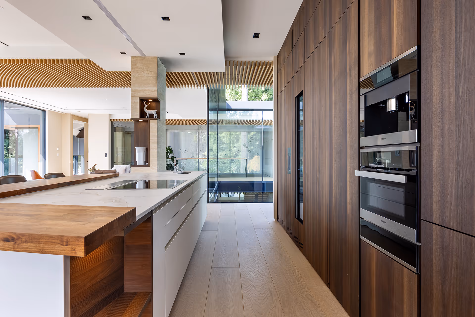 Modern kitchen with wood cabinetry, built-in appliances, and island, residential interior photography