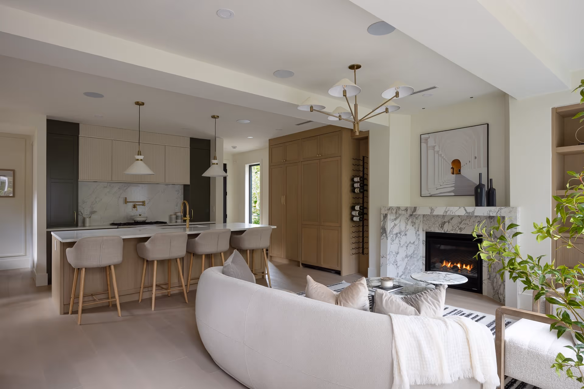 Open-concept living room and kitchen with fireplace, island seating, and natural light, residential interior photography