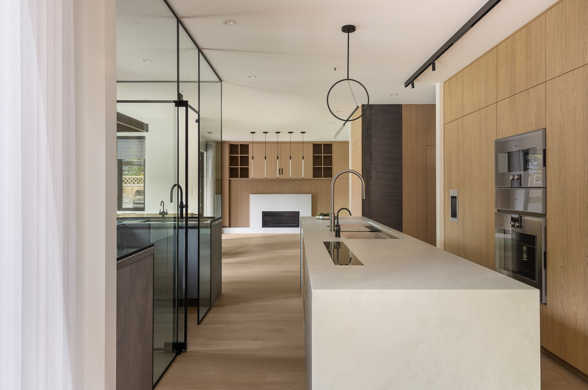 Wide view of The Oku House kitchen and living area with fireplace, Japandy minimalist design by K3N Studio
