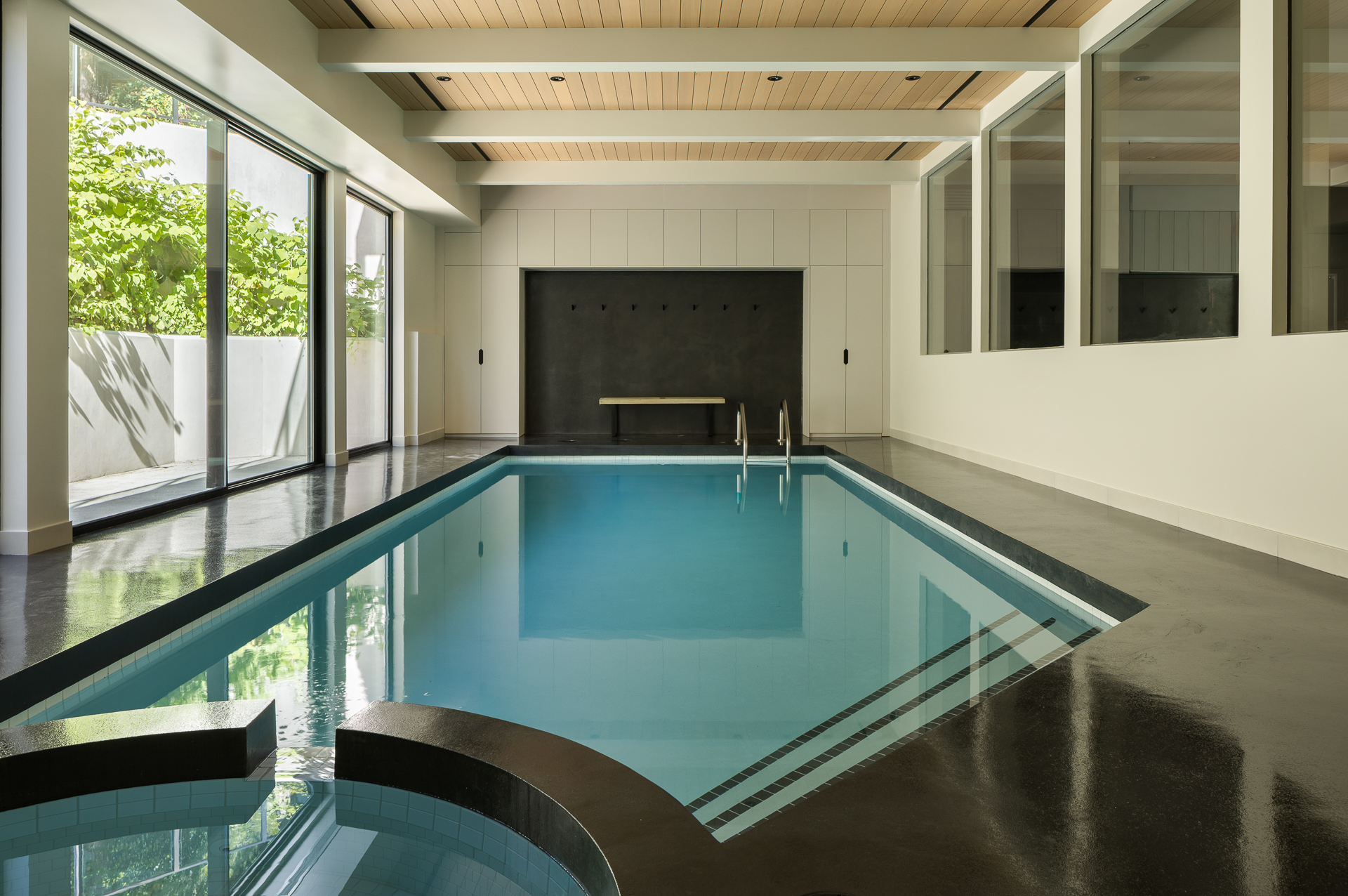 Indoor pool corridor with glass wall opening to exterior stairs and garden, The Oku House