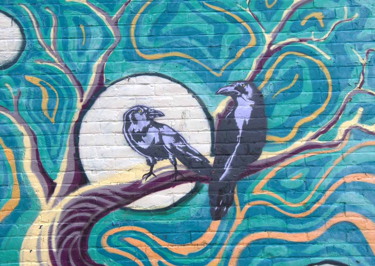 Blue and yellow mural of two crows sitting on a tree branch in front of the moon.