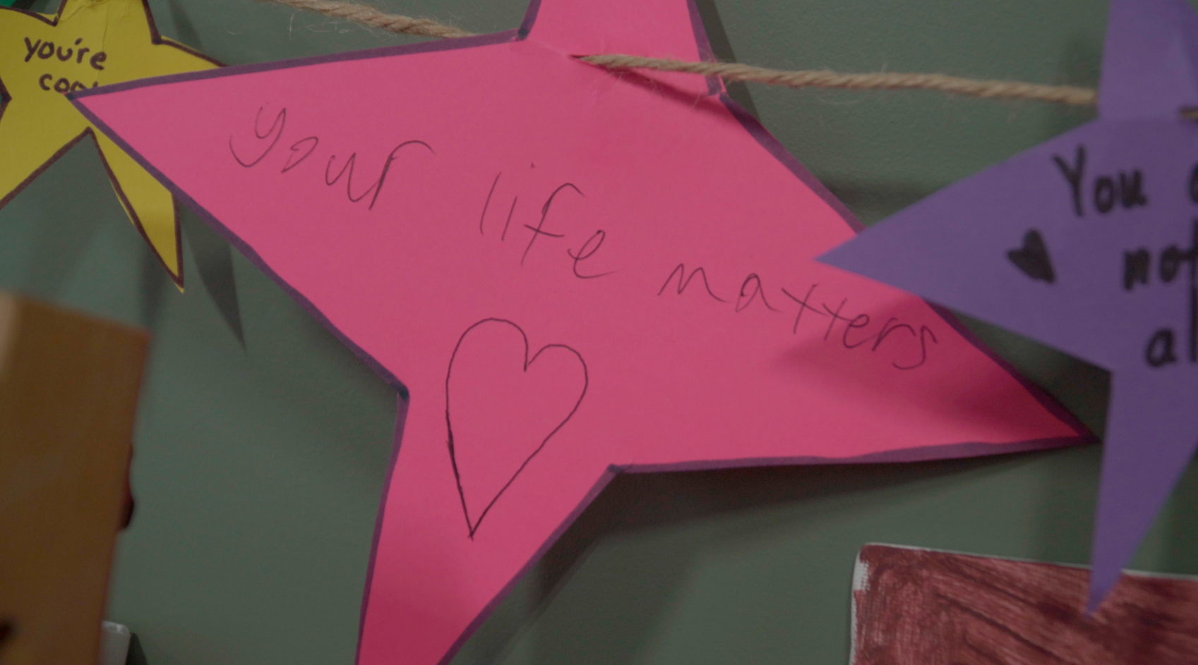 Pink paper cut out star saying "your life matters" with a heart