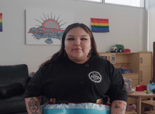 Photo of Teonna McKay in her office with a pride flag behind her