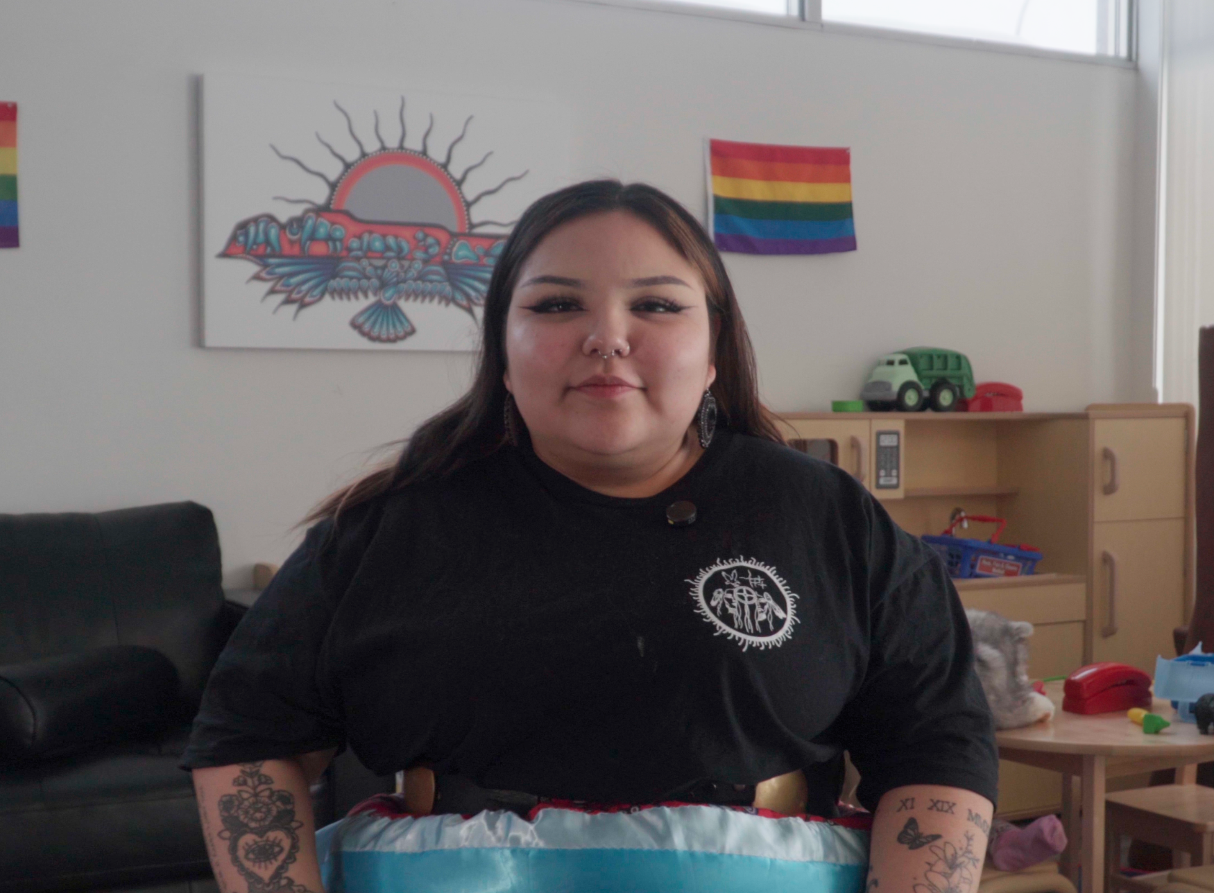 Photo of Teonna McKay in her office with a pride flag behind her