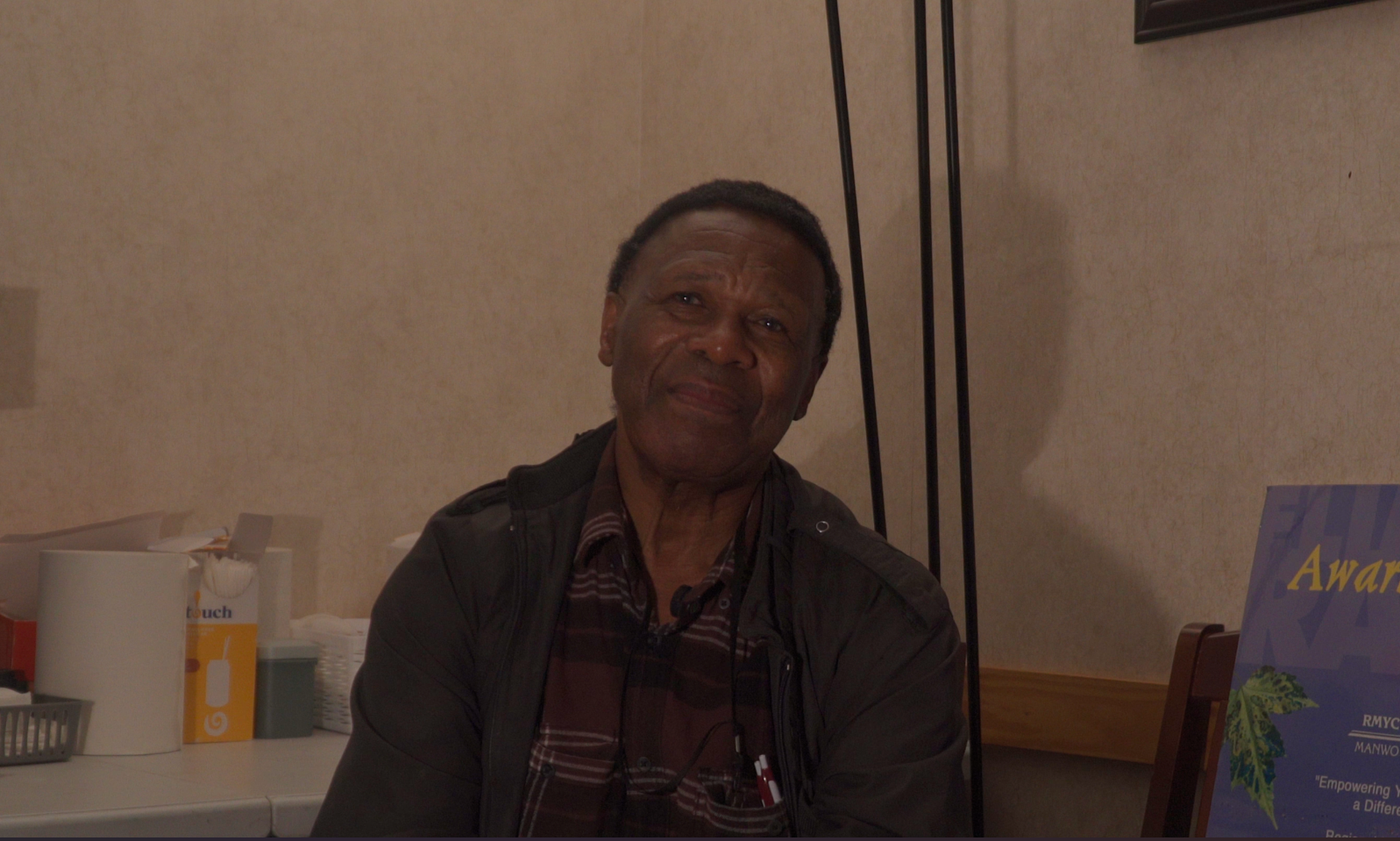 Photo of Moffat Makuto smiling in a plaid shirt