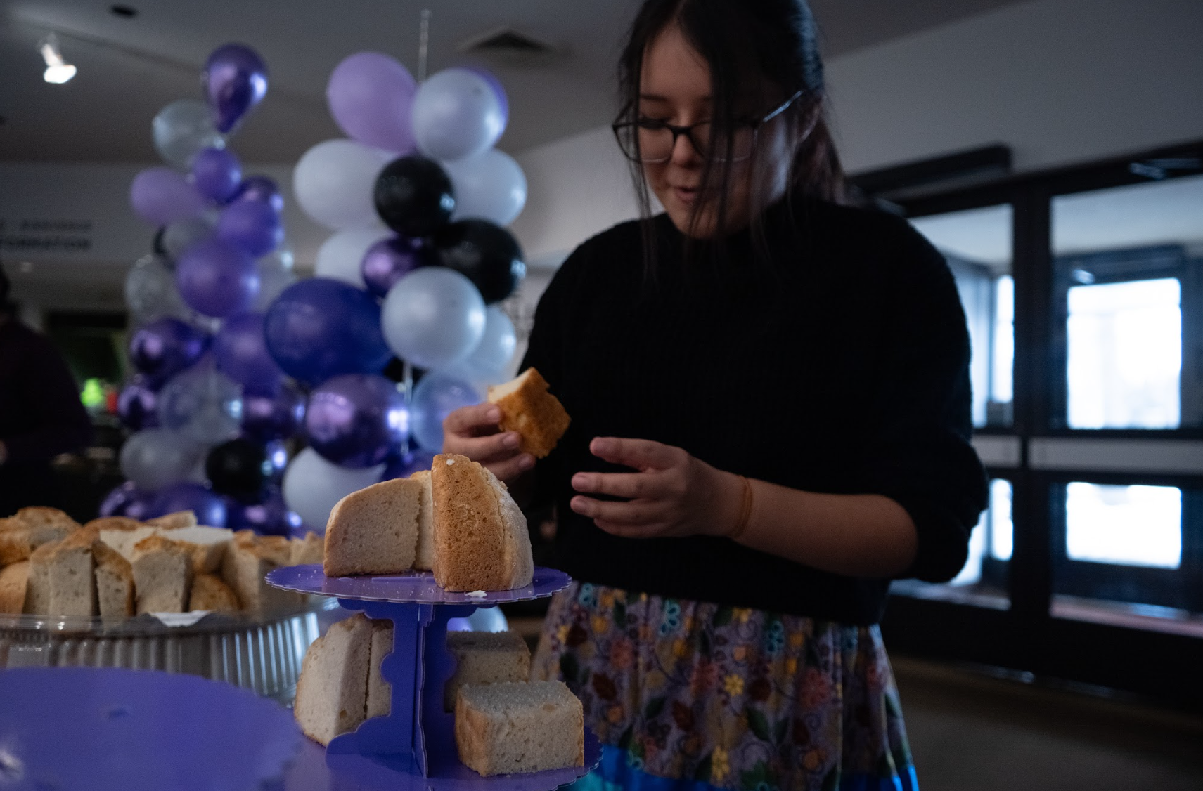 A gilr picking up some bannock to eat from the table