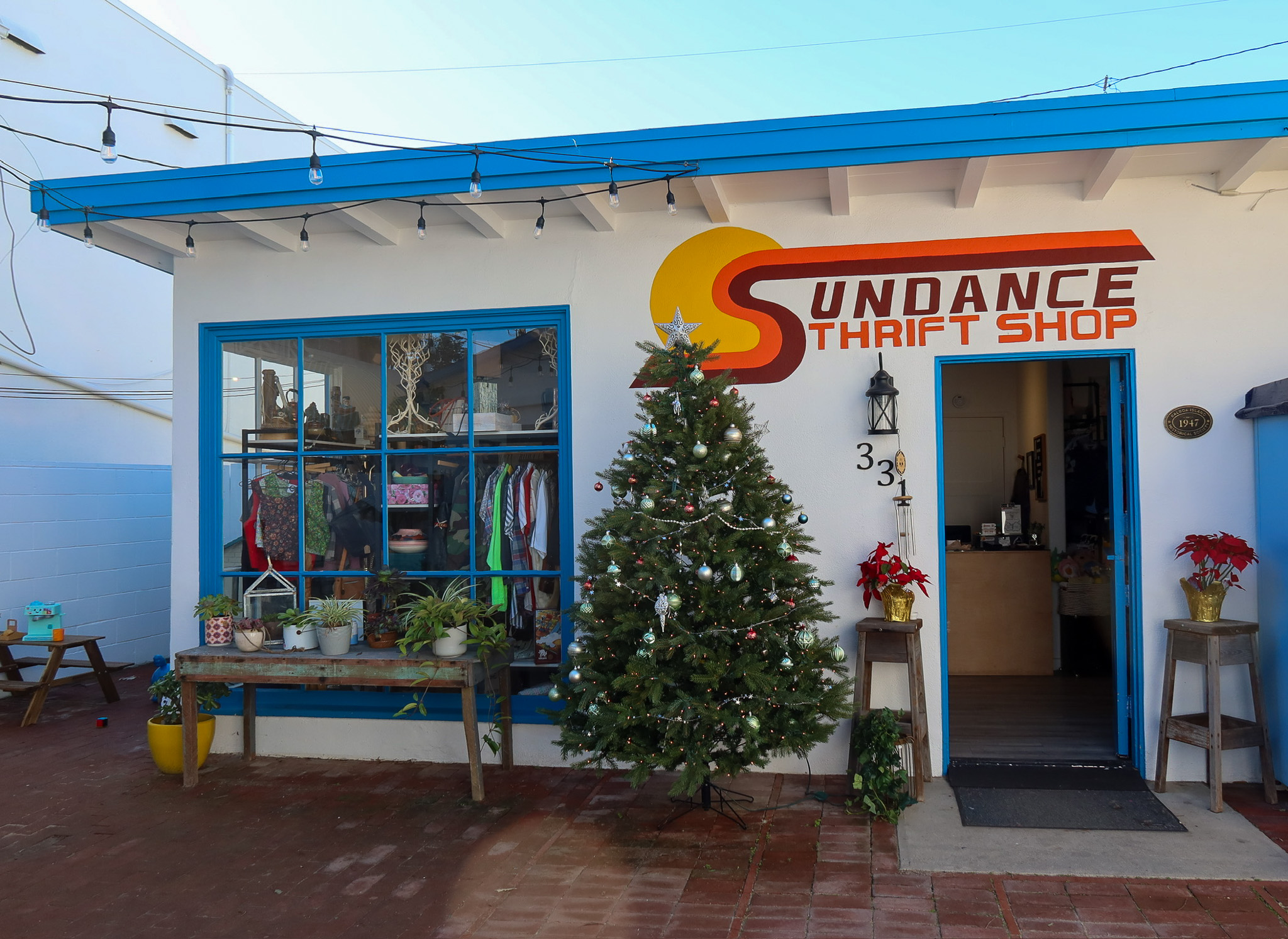 courtyard entrance to sundance thrift shop on balboa island with blue photo booth and yellow umbrella