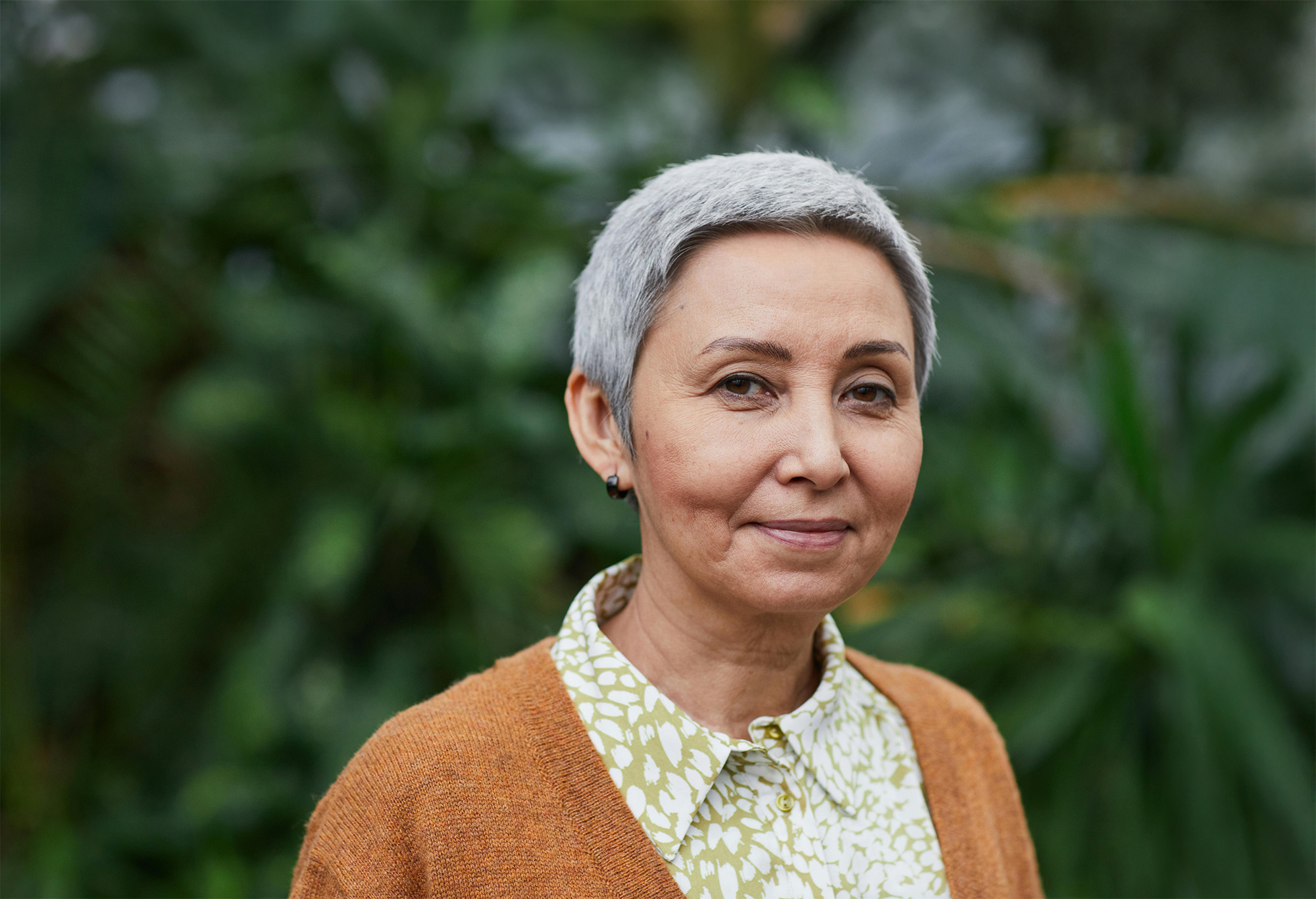Rocky coastline with cliffs and waves crashing into a small sandy beach beneath a cloudy sky.